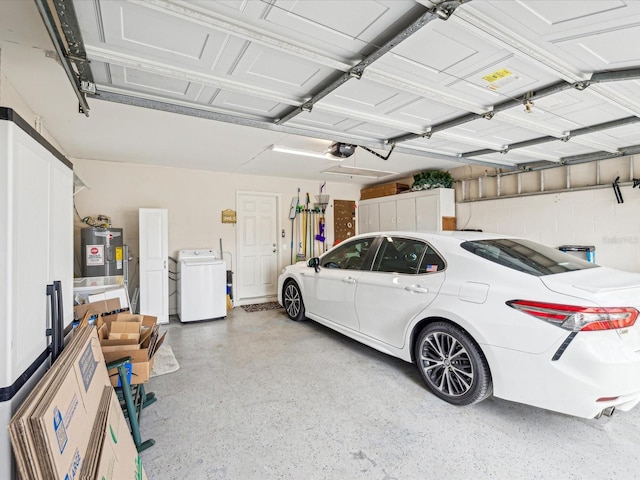 garage featuring electric water heater, a garage door opener, and washer / dryer