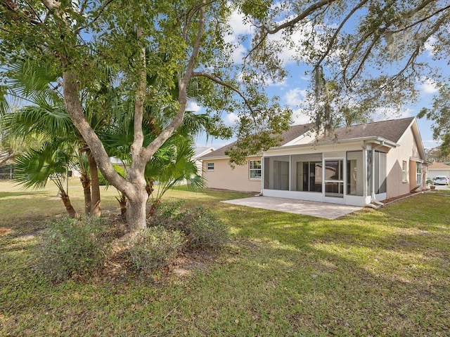 back of house featuring a lawn, a sunroom, and a patio