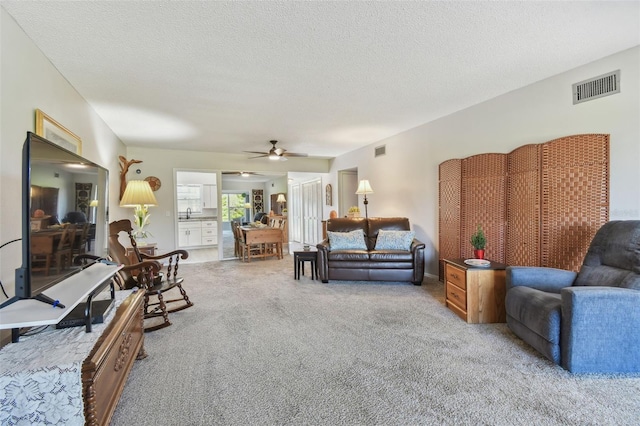 carpeted living room featuring ceiling fan and a textured ceiling