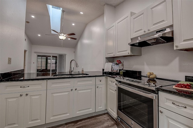 kitchen with white cabinetry, sink, ceiling fan, stainless steel range with electric stovetop, and vaulted ceiling with skylight