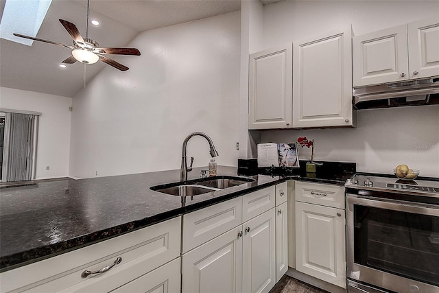 kitchen with white cabinetry, electric range, sink, dark stone counters, and vaulted ceiling with skylight