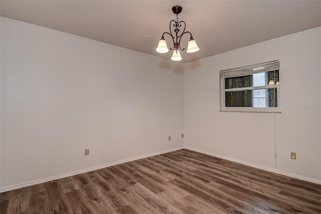 unfurnished room with dark hardwood / wood-style floors, a textured ceiling, and a notable chandelier