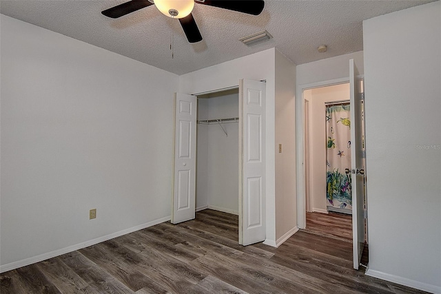 unfurnished bedroom with ceiling fan, a closet, dark hardwood / wood-style floors, and a textured ceiling