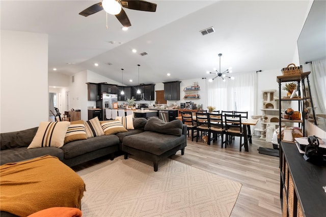 living room featuring ceiling fan with notable chandelier, light hardwood / wood-style flooring, and vaulted ceiling