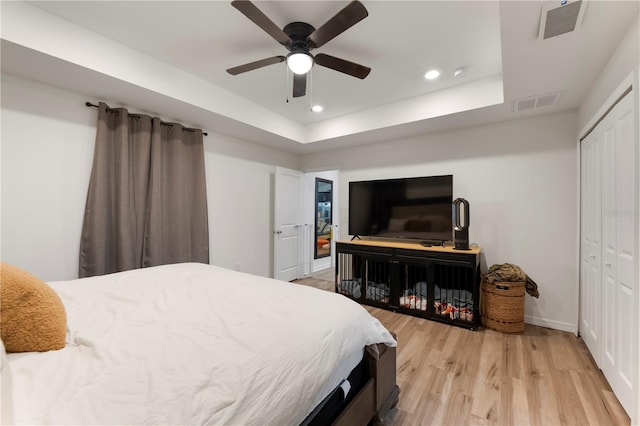 bedroom featuring ceiling fan, hardwood / wood-style flooring, a tray ceiling, and a closet