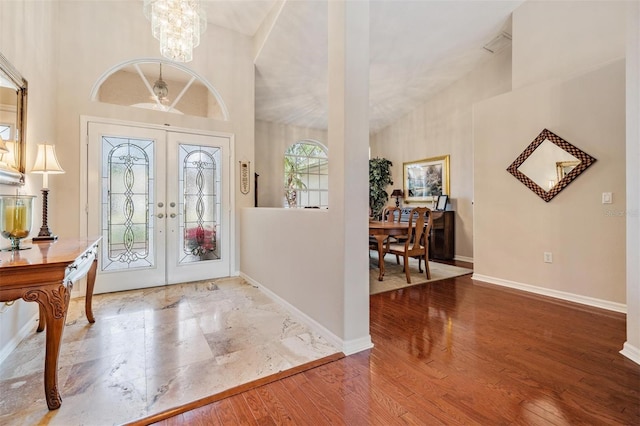 entryway featuring french doors, ceiling fan with notable chandelier, high vaulted ceiling, and hardwood / wood-style floors