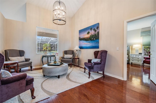 sitting room featuring dark hardwood / wood-style flooring, a towering ceiling, and a notable chandelier