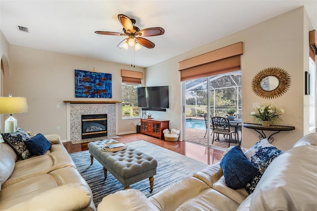 living room featuring ceiling fan, a fireplace, and hardwood / wood-style floors