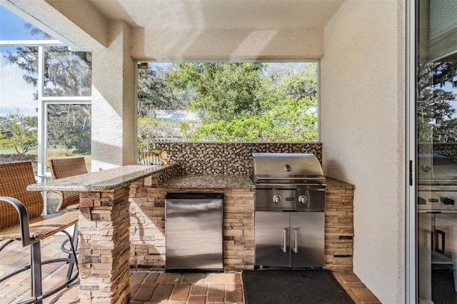 view of patio featuring area for grilling, a bar, and exterior kitchen