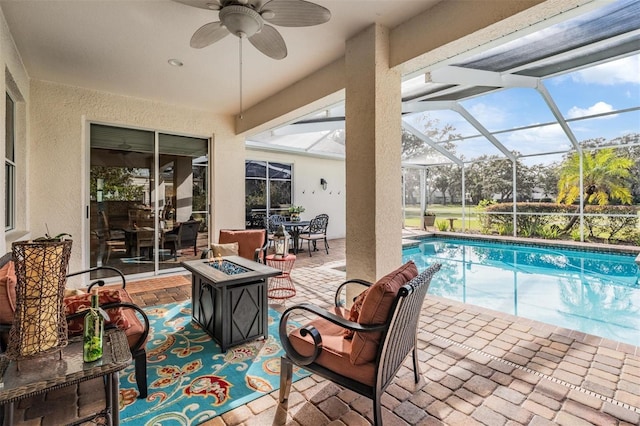 view of swimming pool with ceiling fan, a patio area, a lanai, and an outdoor fire pit