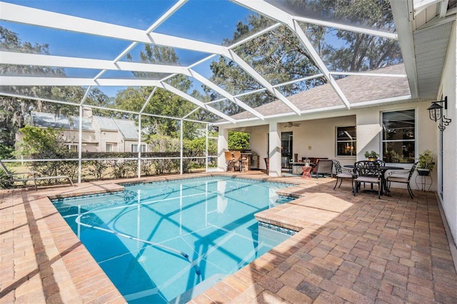 view of pool featuring glass enclosure, ceiling fan, and a patio