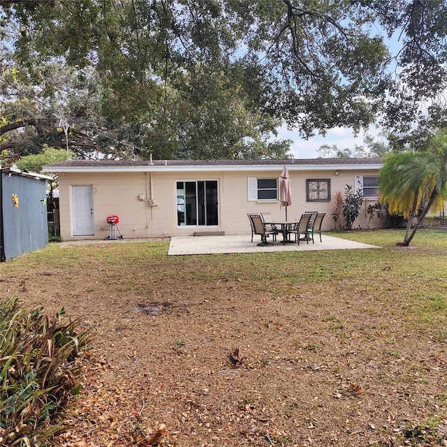 rear view of house featuring a lawn and a patio