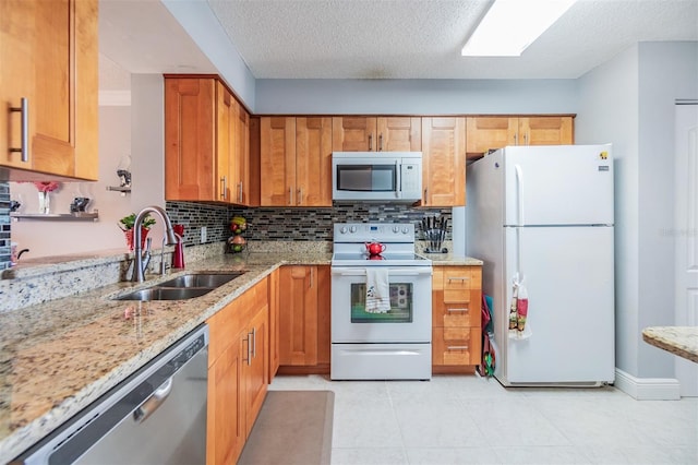 kitchen with white appliances, sink, decorative backsplash, a textured ceiling, and light stone counters