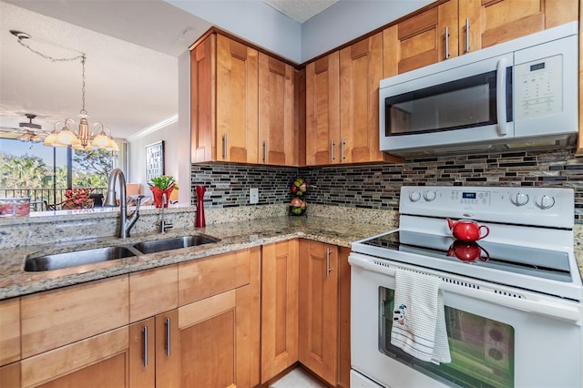 kitchen with sink, tasteful backsplash, light stone counters, a chandelier, and white appliances