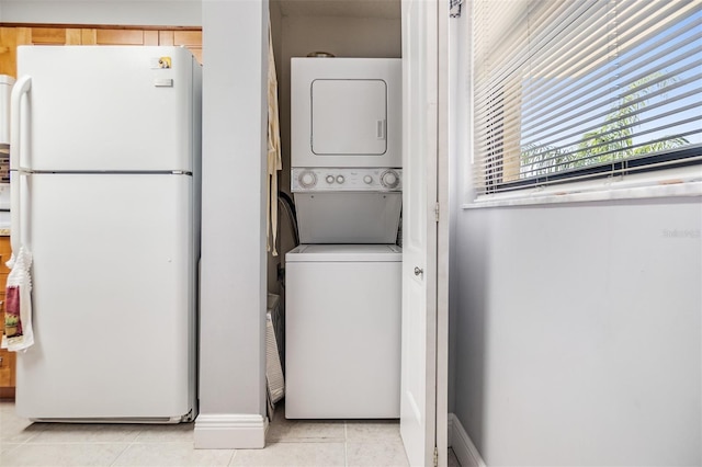 laundry room featuring light tile patterned floors and stacked washer and clothes dryer