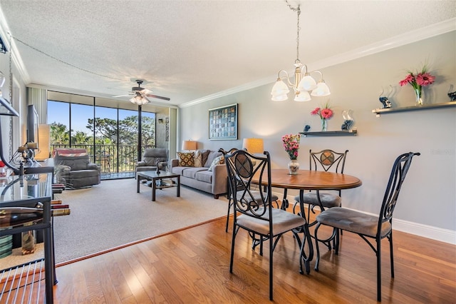 dining room featuring crown molding, expansive windows, ceiling fan with notable chandelier, and a textured ceiling