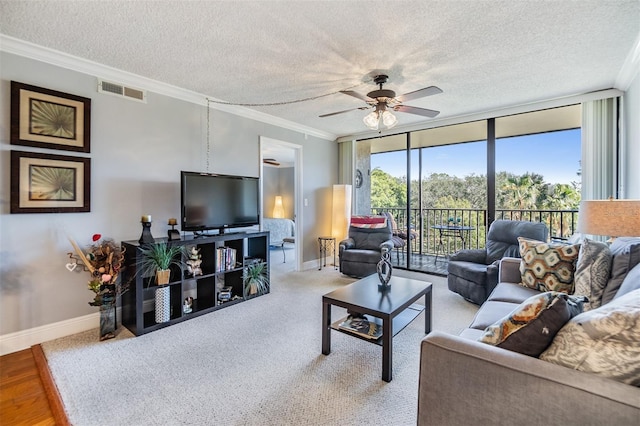 living room featuring crown molding, ceiling fan, a textured ceiling, and a wall of windows