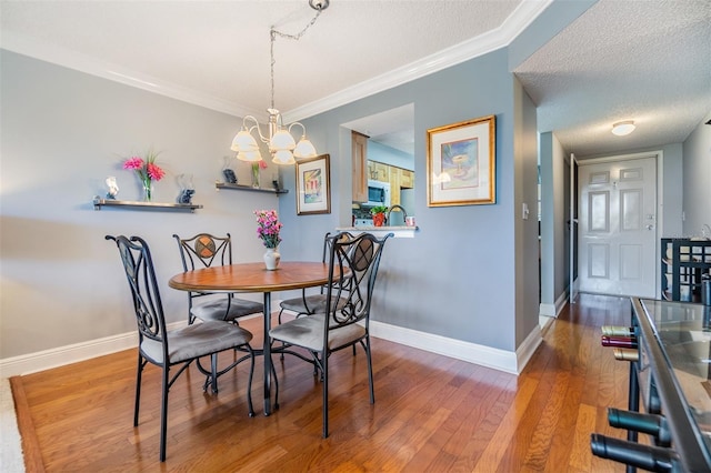 dining room with wood-type flooring, ornamental molding, a textured ceiling, and an inviting chandelier