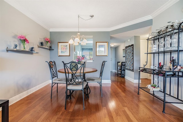 dining area featuring hardwood / wood-style flooring, crown molding, and an inviting chandelier