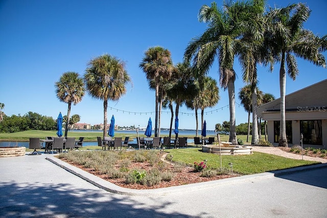 surrounding community with a water view and a yard