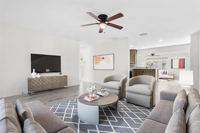 living room featuring ceiling fan, sink, and dark wood-type flooring