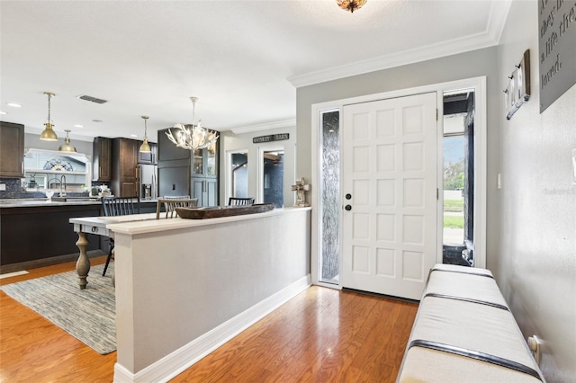 entrance foyer with light hardwood / wood-style flooring, crown molding, and a chandelier