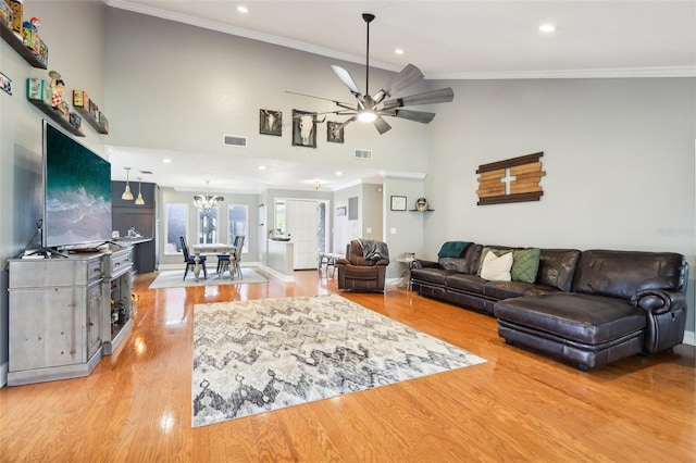 living room featuring light hardwood / wood-style floors, ceiling fan with notable chandelier, and ornamental molding