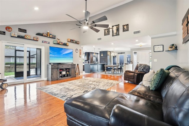 living room featuring ceiling fan, high vaulted ceiling, wood-type flooring, and ornamental molding