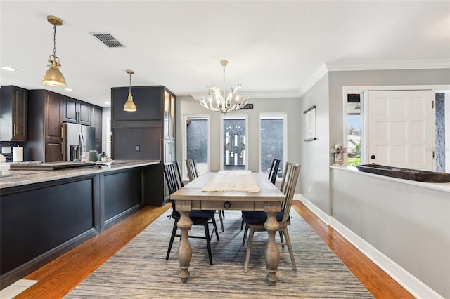 dining space featuring a chandelier, hardwood / wood-style flooring, and ornamental molding