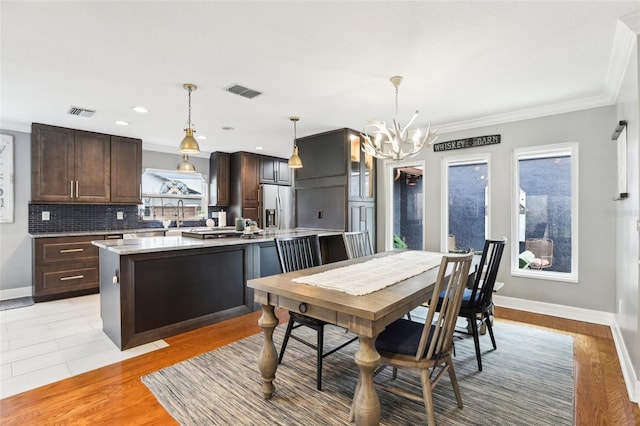 dining room featuring crown molding, sink, a notable chandelier, and light wood-type flooring