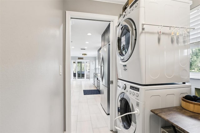 washroom with stacked washer and dryer and light tile patterned floors