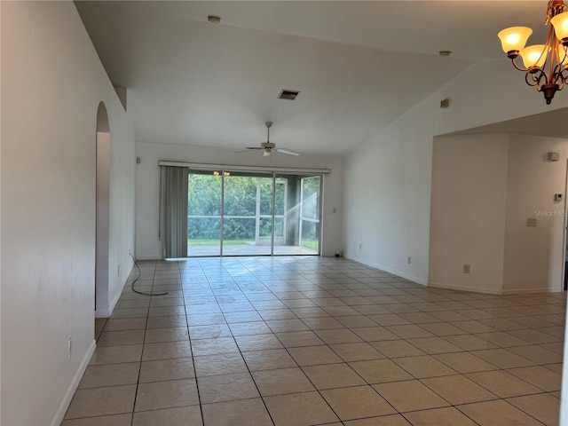 empty room featuring ceiling fan with notable chandelier, light tile patterned flooring, and vaulted ceiling