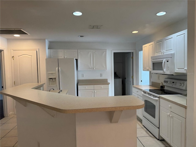 kitchen with a kitchen breakfast bar, white appliances, a center island, and white cabinetry