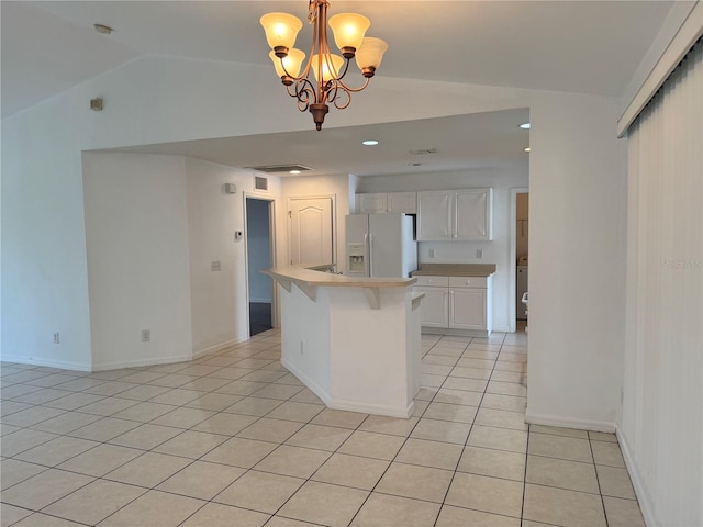 kitchen featuring white fridge with ice dispenser, a kitchen island, a chandelier, decorative light fixtures, and white cabinets