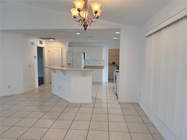 kitchen with white fridge with ice dispenser, hanging light fixtures, a kitchen island, a notable chandelier, and white cabinets