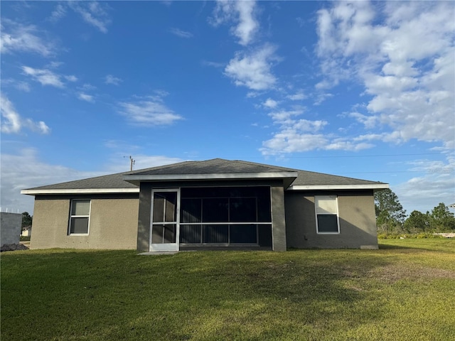 back of house featuring a sunroom and a lawn