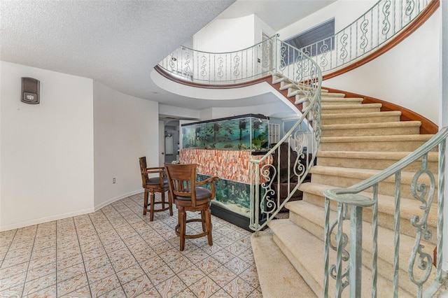 stairway with tile patterned floors and a textured ceiling