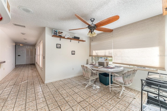 unfurnished dining area featuring ceiling fan, light tile patterned floors, and a textured ceiling