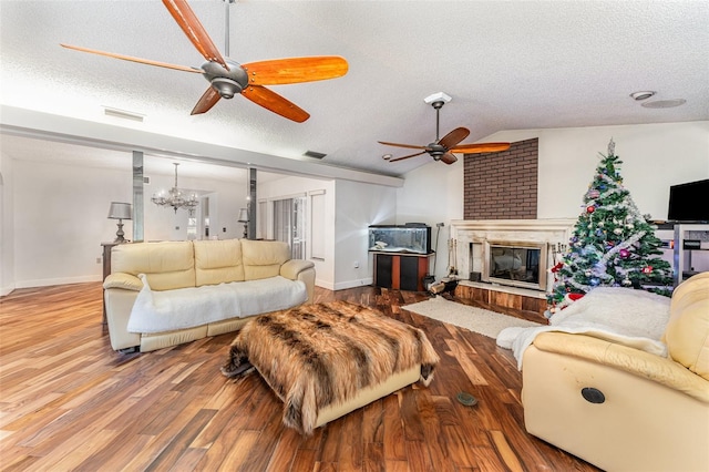 living room featuring lofted ceiling, a fireplace, hardwood / wood-style floors, and a textured ceiling