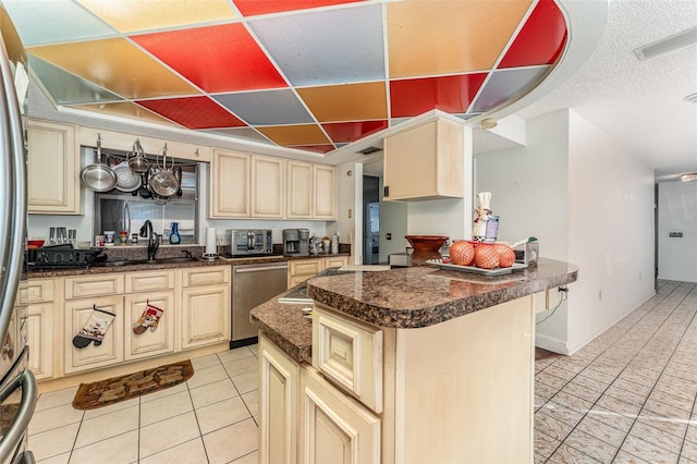 kitchen featuring stainless steel dishwasher, light tile patterned floors, a kitchen island, and cream cabinetry