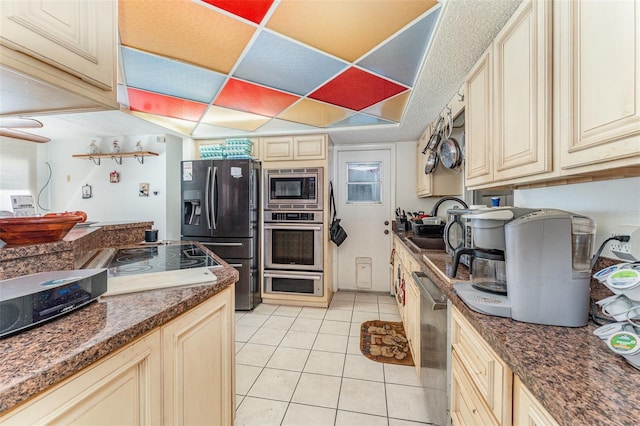 kitchen featuring light tile patterned flooring, appliances with stainless steel finishes, a paneled ceiling, sink, and cream cabinetry