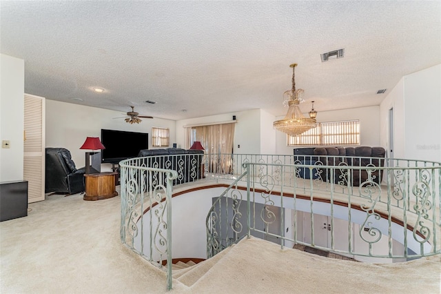 staircase featuring ceiling fan, carpet floors, and a textured ceiling