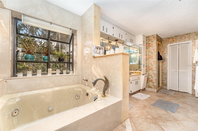 bathroom with a relaxing tiled tub, vanity, tile patterned flooring, and a textured ceiling