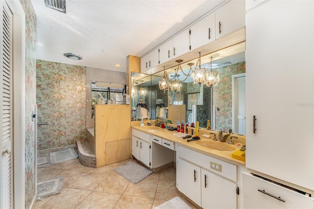 bathroom with an inviting chandelier, tile patterned floors, vanity, and a textured ceiling