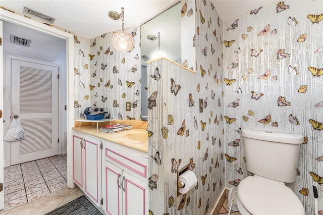 bathroom with vanity, toilet, and a textured ceiling