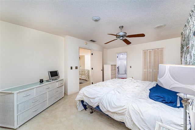 carpeted bedroom featuring ceiling fan, a closet, and a textured ceiling