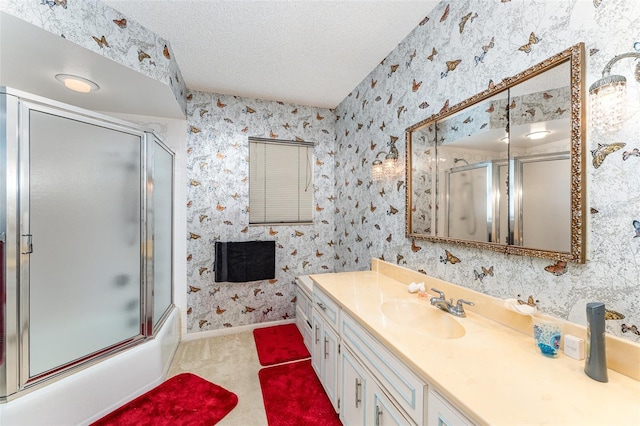 bathroom featuring vanity, enclosed tub / shower combo, and a textured ceiling