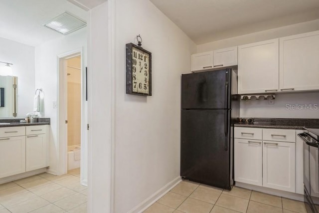 kitchen with white cabinets, black refrigerator, stove, and light tile patterned flooring