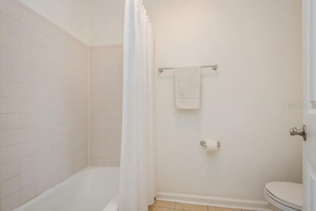 bathroom with tile patterned floors, shower / bath combination with curtain, and toilet