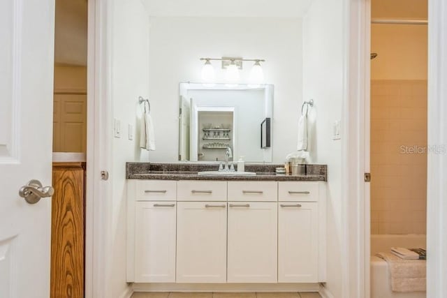 bathroom with tile patterned flooring, vanity, and tiled shower / bath